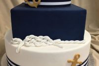 a nautical wedding cake with navy stripes and a navy tier, rope and gold acnhors is a gorgeous idea to rock