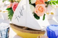 a nautical wedding centerpiece of a boat, blush, coral and white blooms and greenery is a very elegant and chic idea