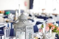 a nautical wedding centerpiece of a candle lantern, candles and neutral and bold blooms is a stylish idea to try