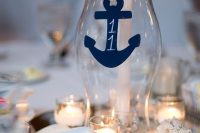 a nautical wedding centerpiece with candles, seashells, a candle lantern with a navy anchor is a lovely idea for a nautical wedding