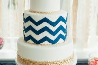 a pretty nautical wedding cake with navy chevrons, gold rope and a navy anchor on top is an amazing idea for a seaside wedding
