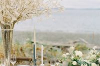 a refined nautical wedding table setting with neutral linens and a navy table runner, blue and white candles, lunaria branches and white blooms