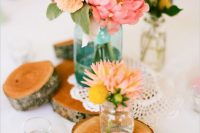 a rustic cluster wedding centerpiece of pink and blush blooms, billy balls, greenery and wood slices is a lovely idea for spring or summer