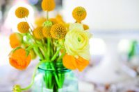 a simple and stylish billy balls and orange and yellow ranunculus wedding centerpiece for a summer wedding