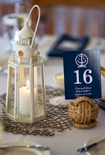 a simple nautical wedding centerpiece with a candle lantern, a piece of net, a rope knot with a table number