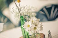 a simple rustic wedding centerpiece of a wood slice, white daisies, baby’s breath and billy balls is an easy idea