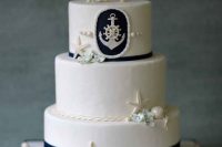 a stylish nautical wedding cake with navy stripes, starfish, seashells and pearls plus an anchor piece for decor is amazing