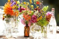 a super colorful and simple wedding centerpiece of pink, orange, yellow, purple and red blooms and greenery for a wildflower wedding