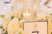 a vintage-inspired wedding centerpiece of white blooms and a candle lantern plus a table number is a chic idea