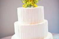 a white buttercream wedding cake lined up with billy balls and decorated with billy balls and blooming branches on top