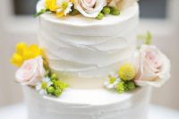 a white textural buttercream wedding cake topped with blush roses, berries, various blooms and billy balls is elegant and cool