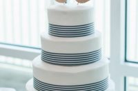 an elegant nautical wedding cake with navy stripes, a seashell, plywood anchors with a bow and a veil is cute and chic