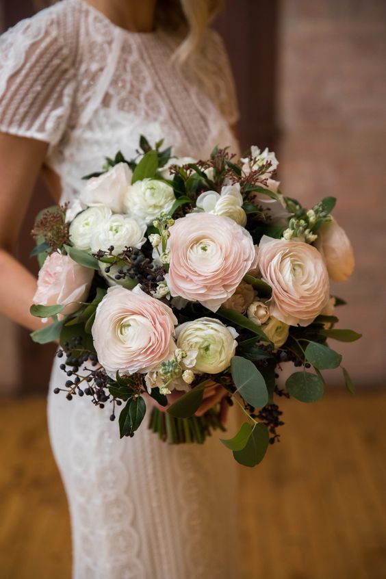 a stylish wedding bouquet of white and blush ranunculus, eucalyptus and privet berries is summer classics for any wedding