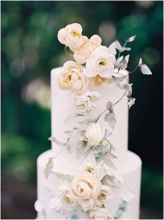 a subtle wedding cake in white, with neutral blooms and spray painted leaves is a very chic and beautiful idea for a secret garden wedding