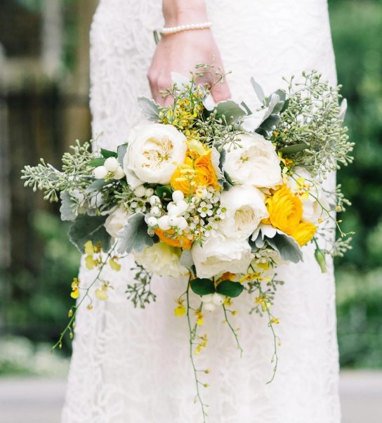 a pretty and bright wedding bouquet of white peonies, yellow ranunculus, greenery, waxflowers and berries is a lovely and bold idea