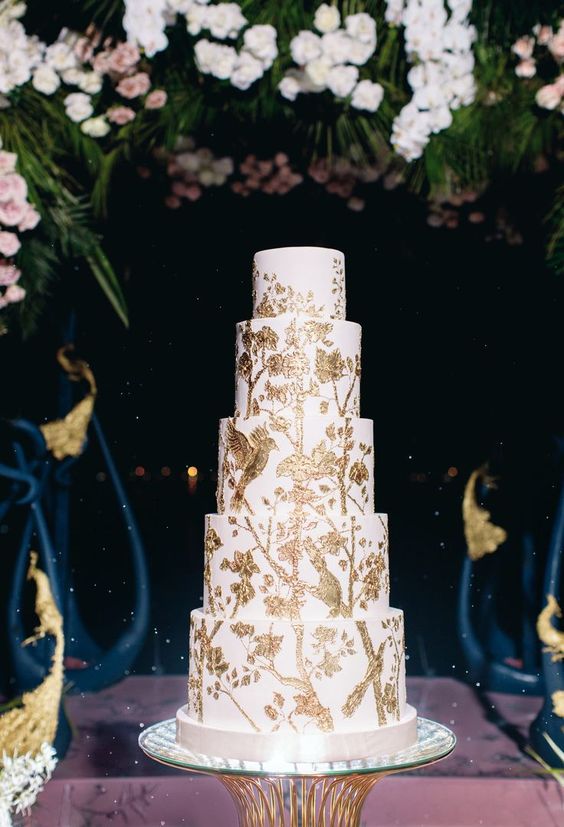 a white wedding cake with gold painted birds, branches and leaves is a very refined and bold idea for a secret garden wedding