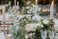 a beautiful and chic wedding centerpiece of white and blush blooms and greenery plus white and blush candles around