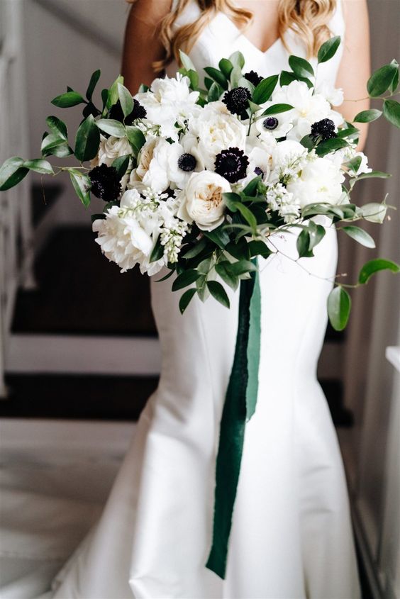 a beautiful wedding bouquet of white peonies, peony roses and anemones, greenery and green ribbons hanging down is awesome