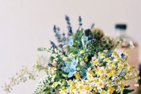 a beautiful wedding centerpiece that includes daisies, privet berries, astilbe, lavender and some more blooms is chic