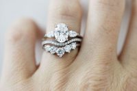 a beautiful white diamond wedding ring stack with an upper oval shaped one, a wavy diamond ring and a lower larger diamond ring