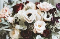 a bold and cool wedding bouquet of burgundy and white roses, blush ones, white anemones, seed pods and thistles, greenery for the fall
