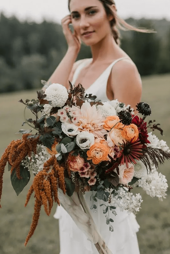 a bold summer wedding bouquet with burgundy, rust, pink, orange and white blooms of various kinds including anemones