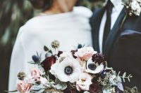 a bold winter wedding bouquet of burgundy and pink roses, white anemones, greenery, thistles and eucalyptus is wow