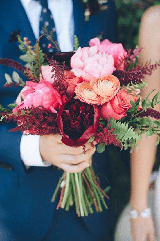 a bright wedding bouquet of pink, deep red and orange blooms, greenery and deep purple flowers for a bright fall wedding