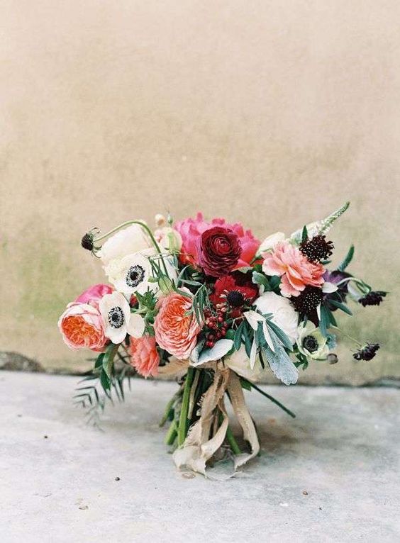 a bright wedding bouquet of white anemones, dark blooms, pink and peachy pink peonies, peony roses and ranunculus and greenery