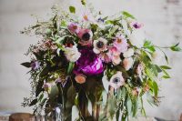 a bright wedding centerpiece of hot pink and white anemones, various types of greenery and a beautiful brass vase is wow
