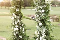 a chic garden wedding arch decorated with greenery and white blooms is a very chic and stylish idea that will never go out of style