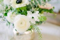 a chic wedding centerpiece of white ranunculus and anemones, greenery and eucalyptus plus a mercury glass vase is pure elegance