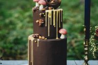 a chocolate wedding cake with creamy drip, sugar mushrooms, nuts and chocolate sphere decor on top looks whimsical and creative