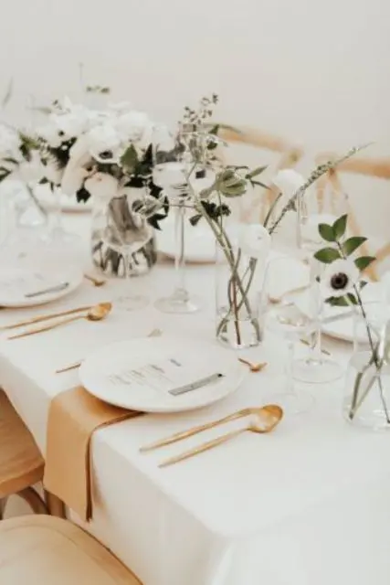 a cluster wedding centerpiece of matching vases with greenery and white anemones is a chic and beautiful idea to try