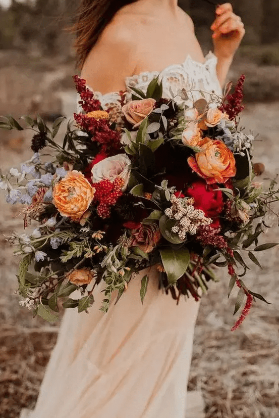 a colorful fall wedding bouquet of orange, pink, red, blue, lilac blooms, foliage and greenery is a catchy fall wedding solution