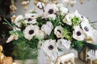 a cool and simple white anemone and evergreen wedding centerpiece in a white vase will match many wedding decor themes