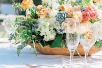 a cool secret garden wedding centerpiece of pink, marigold, white blooms, thistles, succulents and greenery is chic