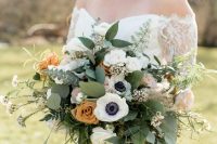 a cool wedding bouquet of white anemones and ranunculus, rust and blush roses, greenery of various kinds is chic and cool