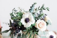 a cool wedding centerpiece of blush roses, white anemones, greenery, privet berries and a cool vase is ideal for spring or summer