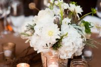 a cute and simple wedding centerpiece of white daisies, hydrangeas and greenery surrounded with candles is ideal for a rustic wedding