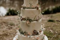 a dreamy enchanted forest wedding cake in white, with sugar patterns, blooms, feathers and berries is a chic idea
