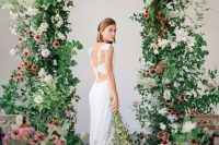 a dreamy garden wedding arch decorated with greenery, white and pink blooms plus arrangements on the floor for a beautiful indoor garden look