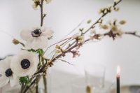 a dreamy minimalist wedding centerpiece of blooming branches and white anemones is a very beautiful idea for a spring wedding