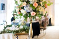 a dreamy tall wedding centerpiece of white, blue and peachy pink blooms and greenery is a lovely and cool idea for a secret garden wedding