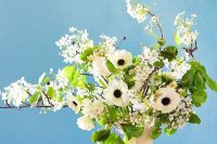 a dreamy wedding centerpiece of white anemones and bird cherry blossoms in a vintage vase is a gorgeous centerpiece for spring or summer
