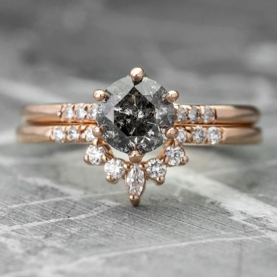 a fantastic rose gold stacjed wedding ring with a black round diamond and an arched smaller diamond ring to frame it is very elegant