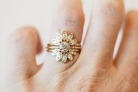 a floral stacked engagement ring with a center round diamond and petal arched upper and lower rings is very cool