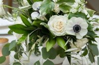 a fresh wedding centerpiece of white peonies and anemones and various types of greenery in a vintage urn is very cool