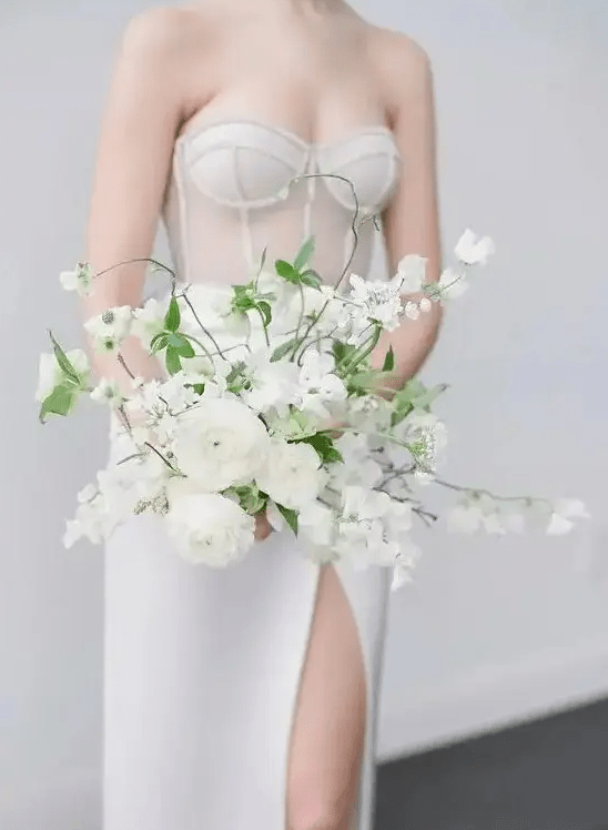 A gorgeous all white wedding bouquet with blooming branches and greenery is a chic idea for a spring or summer bride