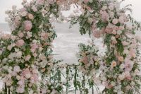 a jaw-dropping beach garden wedding arch decorated with greenery, white, blush and mauve blooms is just jaw-dropping and chic